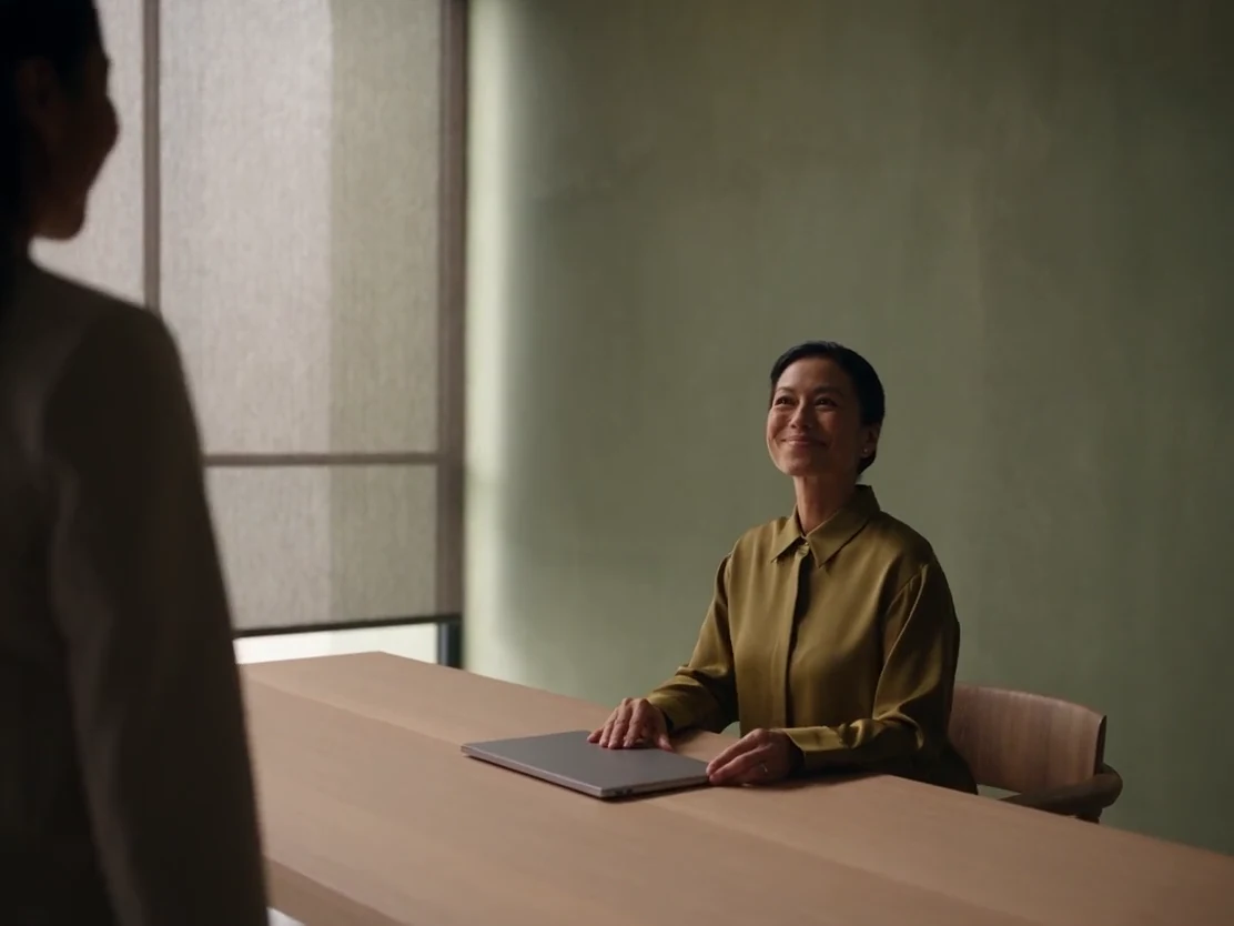 A Willow Studio manager closes her laptop and warmly welcomes a customer.